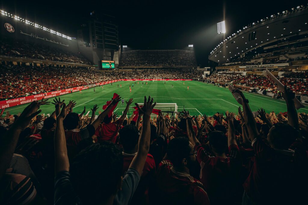 Lively football match with cheering fans in Abu Dhabi stadium at night.